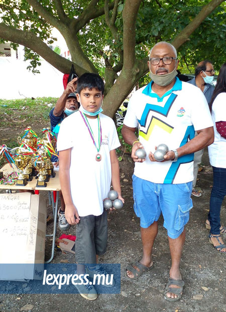 Un enfant se faisant prendre en photo à Mahébourg auprès des trophées récompensant ceux ayant participé au tournoi du 5 septembre